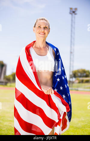 Athlète féminine heureuse enveloppée de drapeau américain Banque D'Images