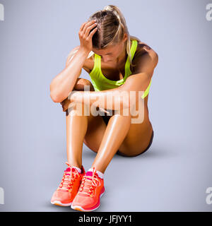 Image composite de femme sportive s'asseoir et de se sentir déçu Banque D'Images