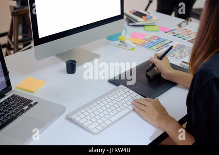 Jeune photographe et graphiste au travail dans bureau. Moniteur écran vide pour montage de l'affichage graphique. Banque D'Images