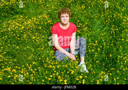 Femme d'âge moyen assis dans champ de fleurs vu du dessus Banque D'Images