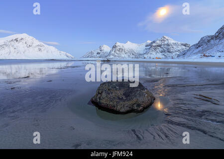 Pleine lune reflétée dans la mer de glace autour de la plage de Skagsanden surréaliste Flakstad Nordland County Iles Lofoten Norvège Europe Banque D'Images