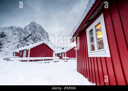 Nuages sur les maisons rouges typiques de pêcheurs appelée Rorbu entouré par snowy Hamnøy Lofoten, Norvège du Nord Europe Banque D'Images