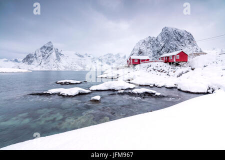 Les sommets enneigés et le châssis de la mer congelés maisons appelées typique de pêcheurs des îles Lofoten Rorbu Hamnøy Europe du nord de la Norvège Banque D'Images