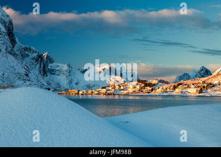 La couleur bleue du crépuscule sur le village de pêcheurs et les cimes enneigées d'Andøya Kvalvika Reine Nordland îles Lofoten Norvège Europe Banque D'Images