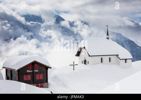 Nuages au-dessus de l'église et des refuges de montagne couverte de neige Bettmeralp Française, canton du Valais Suisse Europe Banque D'Images