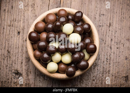 Assortiment de pralines en chocolat bol en bois, on wooden table Banque D'Images