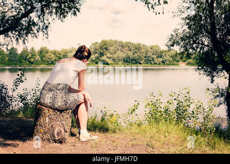 Une triste et nostalgique femme est assis près de le Dniepr à Kiev, Ukraine. Elle se dit en regardant ou en observant de loin dans la distance, und Banque D'Images