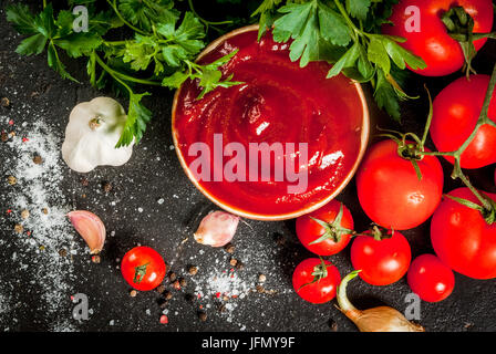 Des tomates biologiques ou sauce ketchup, dans un petit bol. Avec les ingrédients - persil, oignons, ail, tomates, sel, poivre. On a black st Banque D'Images