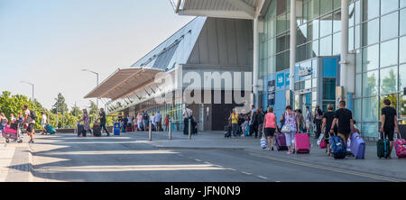 Les passagers aériens arrivant à l'aéroport de Birmingham, UK de quitter le terminal et de marcher jusqu'à la location de parcs, de taxis et des arrêts de bus. Banque D'Images