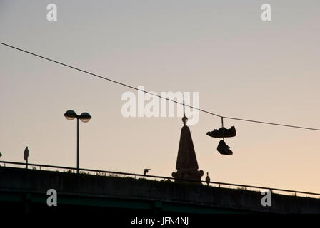 Silhouette de shoes hanging sur le câble sur la ville Banque D'Images