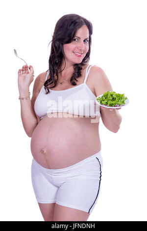 Une femme enceinte avec de manger de la salade et de porter des vêtements blancs. Banque D'Images