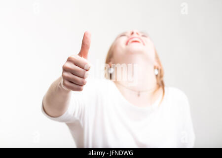 Happy Laughing woman giving Thumbs up un geste avec sa tête rejetée en arrière pour signaler son succès ou la victoire avec l'accent de sa main Banque D'Images