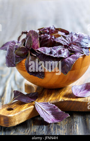 Feuilles fraîches de basilic pourpre dans un bol en bois. Banque D'Images