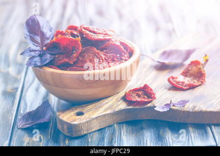 Les tomates séchées dans un bol et une planche de bois. Banque D'Images