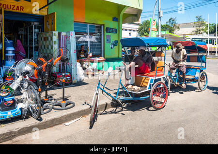 Toamasina, Madagascar - Le 22 décembre 2017 : conducteur de pousse-pousse malgache se reposant dans son pousse-pousse, padicab typique de transport traditionnels à Toamasina Banque D'Images