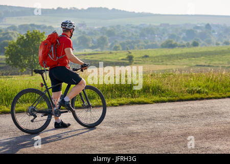 L'écotourisme en Europe. Course cycliste dans le pays. Cycliste voyageur avec sac à dos sur l'aventure a country road. Cycliste à casque blanc un Banque D'Images