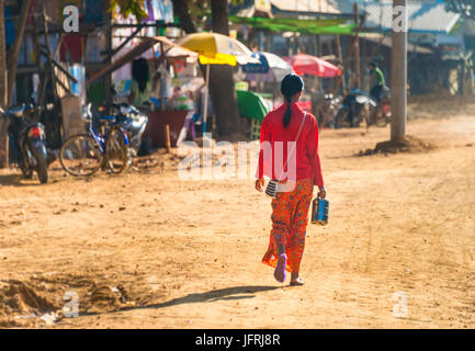 Jeune femme autochtone en robe traditionnelle colorée la marche, scène de rue, Chaung Tha Beach, Myanmar Banque D'Images