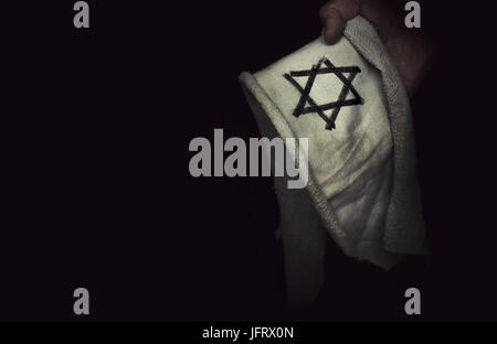 Gros plan de l'insigne juif étoile de David dans la main. Le concept de la mémoire du génocide des Juifs par les Nazis pendant la seconde guerre mondiale. Banque D'Images