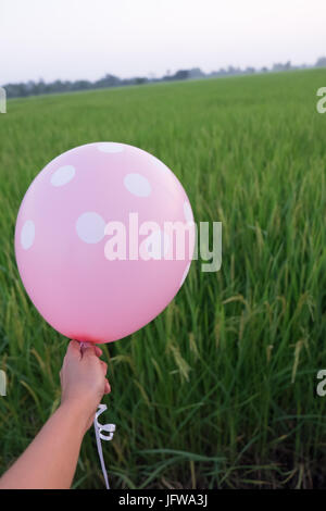 Tenir la main rose blanc points blancs balloon maquette isolée. Maquette Baloon art design. Motif, logo, arrière-plan naturel Banque D'Images