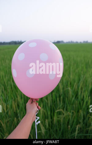 Tenir la main rose blanc points blancs balloon maquette isolée. Maquette Baloon art design. Motif, logo, arrière-plan naturel Banque D'Images