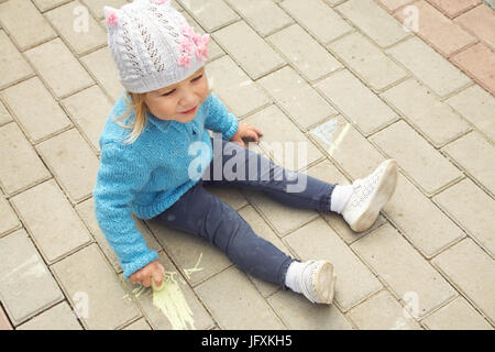 Petite fille attire la craie sur l'asphalte. enfant jouant à l'air libre à l'été Banque D'Images