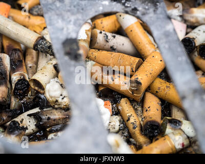 Entêter les cigarettes dans un cendrier public à Londres au Royaume-Uni. Mégots de cigarettes jetés. Extrémités de chien écartées. Banque D'Images