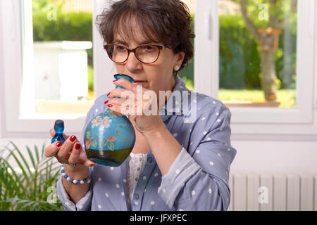 Une femme qui sent une bouteille de liqueur de Banque D'Images