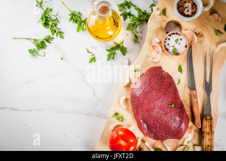 La cuisson du filet de bœuf farci. Grande pièce de filet de veau sur une planche à découper à l'aide d'une fourchette pour la viande, les épices (sel, poivre, persil, ail, oignons, Banque D'Images