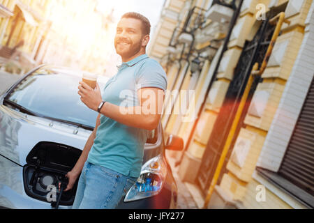 Jeune homme charger sa voiture et boire du café Banque D'Images