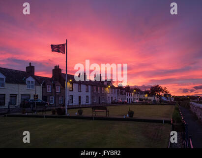 Garlieston de boules et shore cottages dans la lumière du soir avec l'éclairage de rue et de soleil rouge vif derrière Banque D'Images