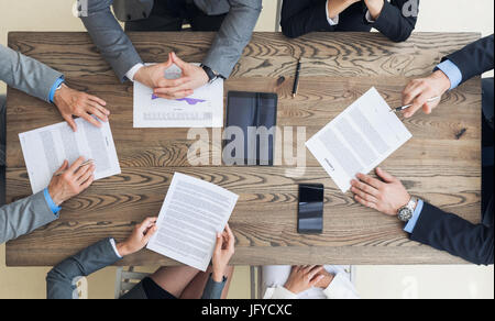 Vue de dessus de business men in suits assis à table en bois et de discuter de nouvelles modalités de contrat avant de le signer Banque D'Images