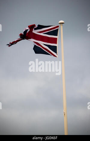 Rupture du Royaume-Uni : un concept et battues déchiré et effiloché Union Jack flag bannière de Grande-Bretagne, volant sur un jour nuageux gris, UK Banque D'Images