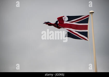 Rupture du Royaume-Uni : un concept et battues déchiré et effiloché Union Jack flag bannière de Grande-Bretagne, volant sur un jour nuageux gris, UK Banque D'Images