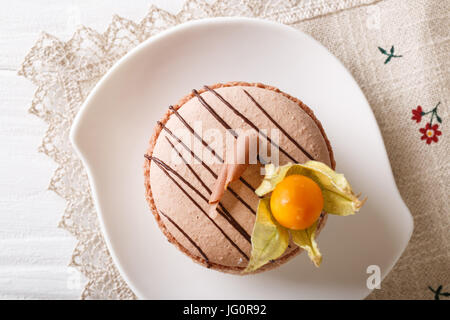 Macaron français décoré avec du chocolat et physalis gros plan sur une plaque horizontale vue du dessus. Banque D'Images