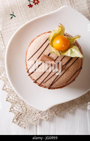 Macaron français décoré avec du chocolat et physalis gros plan sur une assiette. vertical Vue de dessus Banque D'Images