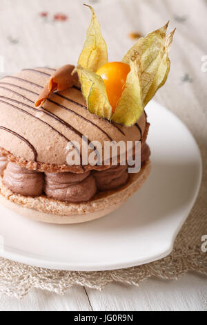 Dessert sucré macaron français : avec crème au chocolat décoré avec des physalis gros plan sur une assiette. La verticale Banque D'Images