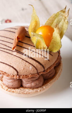 Macaron français farci de crème au chocolat décoré avec des physalis gros plan sur une assiette. La verticale Banque D'Images