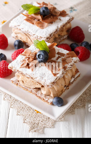 Le Millefeuille avec la crème à café, décoré de fruits rouges et de menthe close-up sur une plaque verticale. Banque D'Images