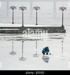 Le pêcheur est la pêche sur la glace d'une rivière gelée dans un matin brumeux. De Dnepropetrovsk, Ukraine Banque D'Images