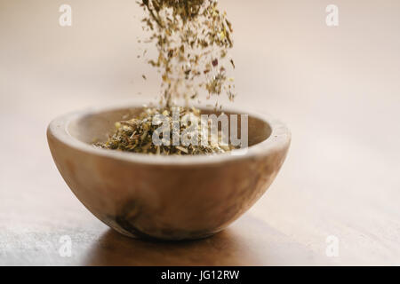 Provence séchées herb mix tomber dans un bol en bois pour l'assaisonnement sur le tableau, l'accent peu profondes Banque D'Images