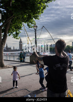 Un musicien ambulant de rue bulles souffle sur la rive sud de la Tamise à Londres avec les Chambres du Parlement et Big Ben en arrière-plan Banque D'Images