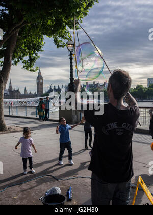 Un musicien ambulant de rue bulles souffle sur la rive sud de la Tamise à Londres avec les Chambres du Parlement et Big Ben en arrière-plan Banque D'Images