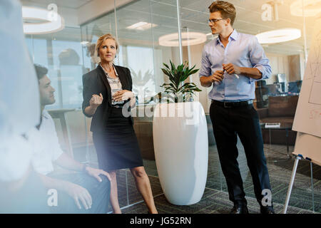 Femme mature en train de discuter avec mes collègues au cours de sa présentation dans un bureau moderne. Les gens d'affaires ayant une réunion de réflexion au bureau. Banque D'Images