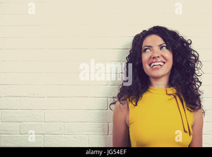 Laughing woman, isolé sur fond mur de brique. L'émotion positive sentiments Banque D'Images