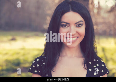 Confiant smiling happy woman, isolé sur fond d'arbres flous. L'émotion positive sentiments Banque D'Images