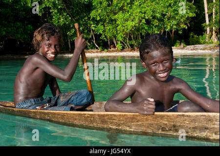 Les jeunes garçons assis dans un canot, lagon de Marovo, Îles Salomon, Pacifique Banque D'Images