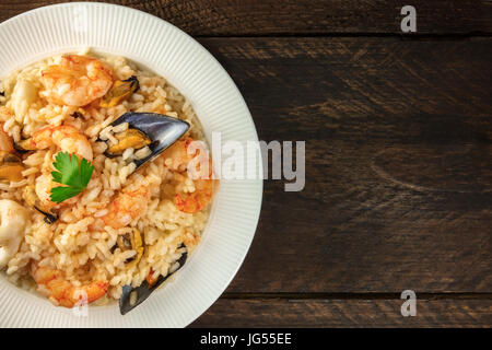 Risotto aux fruits de mer sombre sur fond rustique avec copyspace Banque D'Images