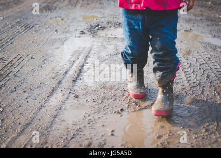 Un enfant marche dans la boue le long d'une route de campagne en Pennsylvanie. Banque D'Images