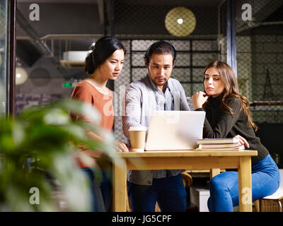 Une équipe d'entrepreneurs asiatique et caucasienne travaillant ensemble dans office à l'aide d'un ordinateur portable. Banque D'Images