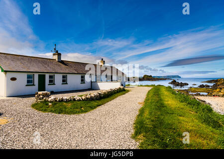 Chalets côte à Ballintoy Harbour, avec un chemin d'allée en gravier. Banque D'Images